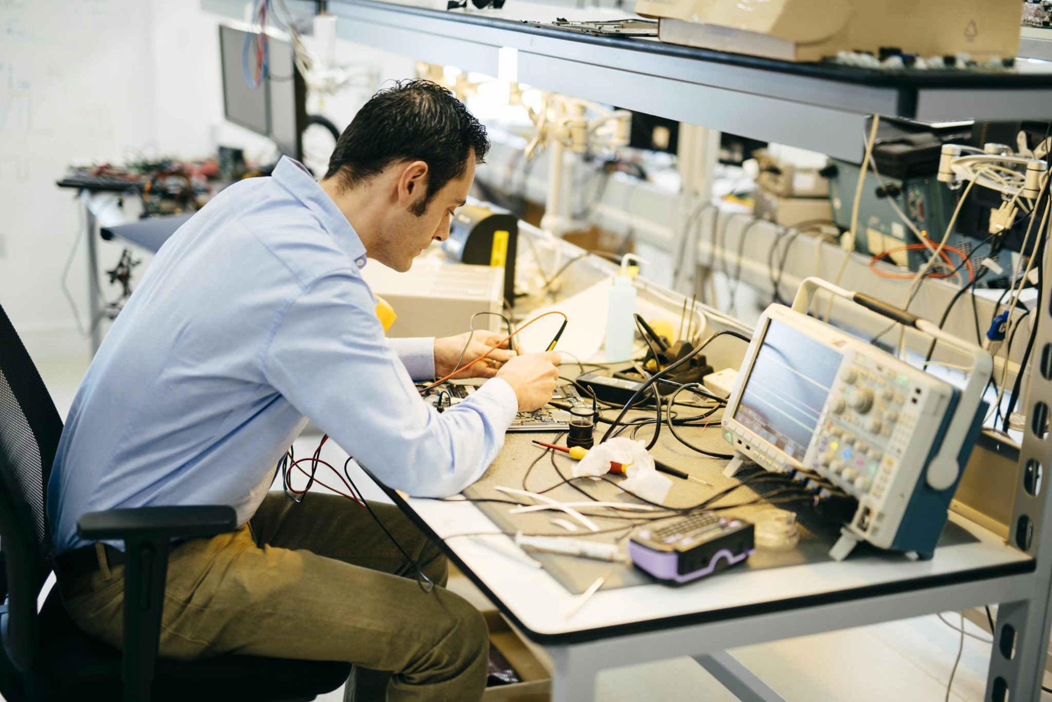 Semiconductor validation engineer working in electronics lab with oscilloscope and testing equipment for chip validation